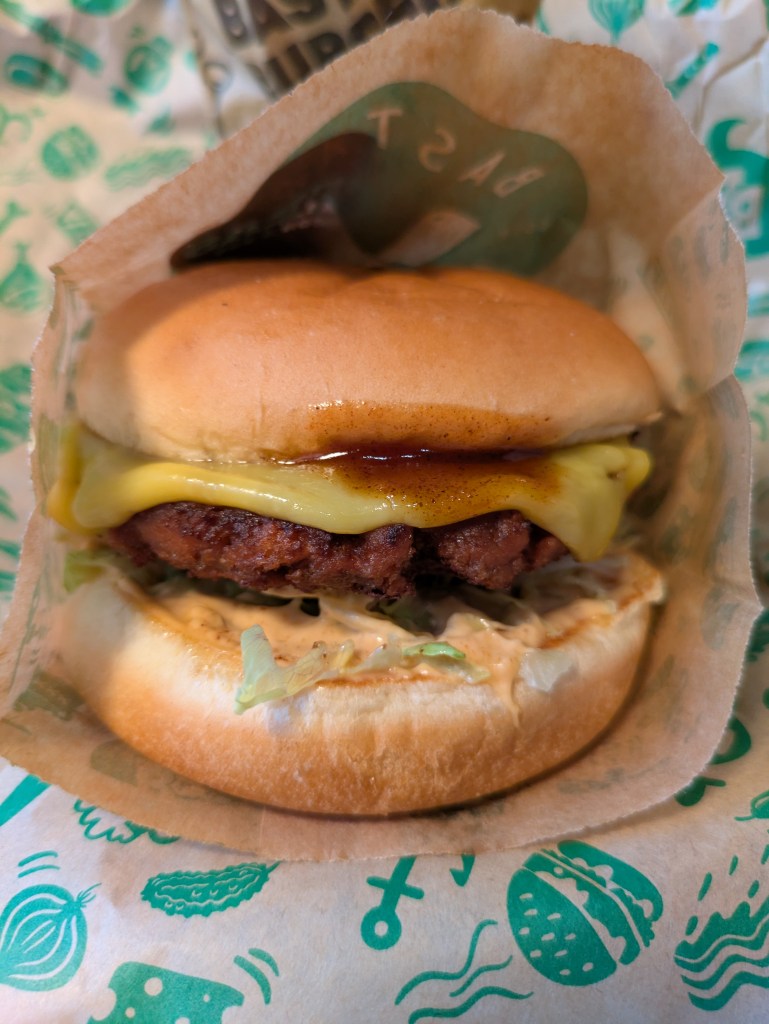 A beef burger topped with a cheese slice and BBQ sauce 